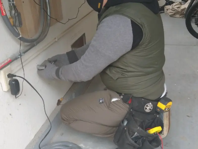 Electrician performing outlet wiring in a Roy garage